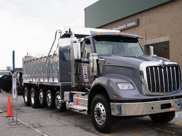 An International Truck HX620 with an S13 Integrated Powertrain, loaded with a dump body, sits in the Vehicle Showcase lot for attendees to see close up.