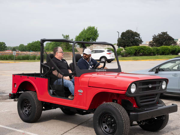 Two people sit in a red Mahindra ROXOR, ready to test drive it.