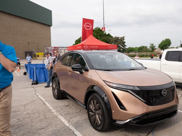 A Sunrise Copper Pearl Nissan ARIYA sits among the Ride & Drive lineup, ready to be taken for a test drive.