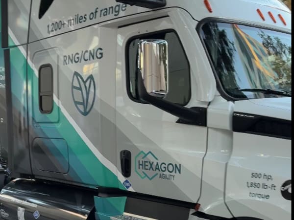 Partial side of white and aqua truck with the words "Hexagon Agility" on the side.