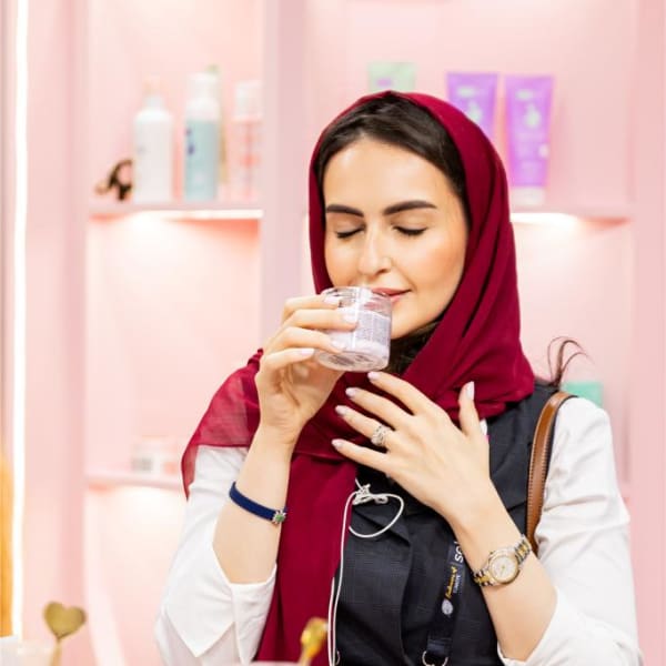 Woman holding a fragrance tester strip and smelling perfume at Beautyworld Middle East 2025.