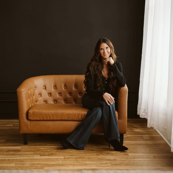 Kati Whitledge sits on a brown couch.