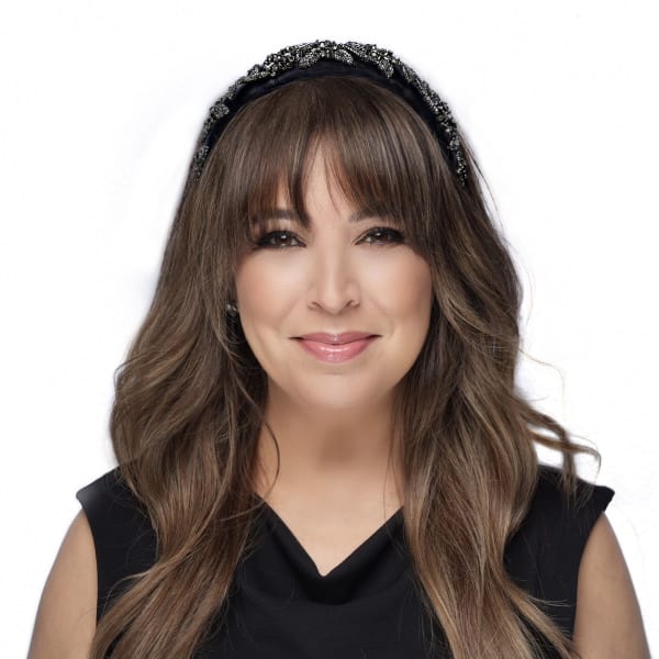 A woman with long brown hair, a black sleeveless blouse, and a beaded headband.