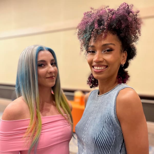 Two models smile for a photo.