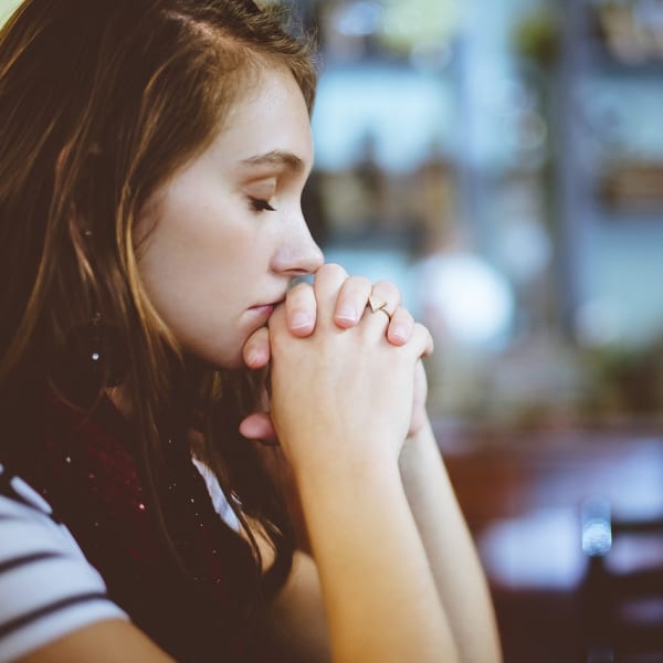 A woman with her eyes closed and hands clasped