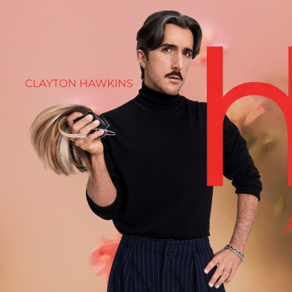 A man in a black turtleneck, holding hair extensions.