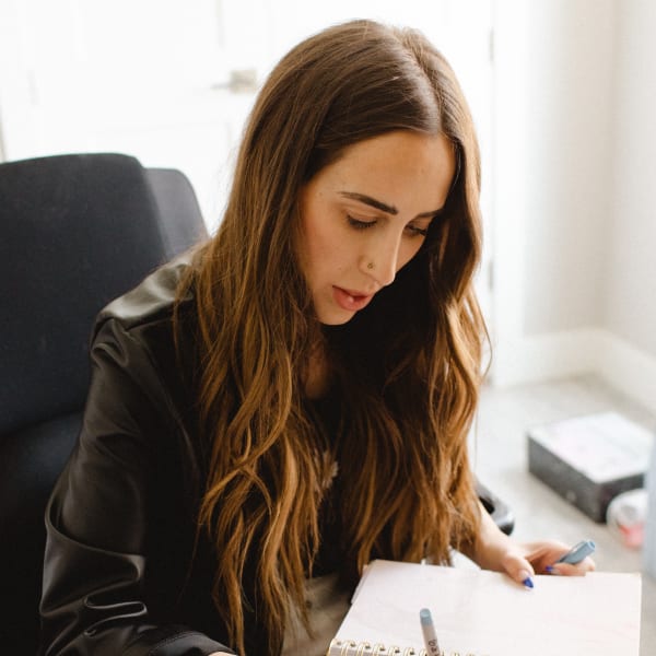 A woman seated at a desk, writing in a calendar.