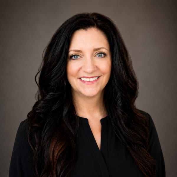 A woman with long dark hair, wearing a black blouse.