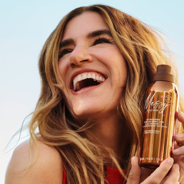 A smiling woman holding a product