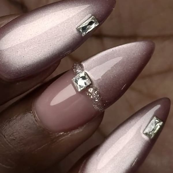 Three fingernails with long pink nails and faux diamonds