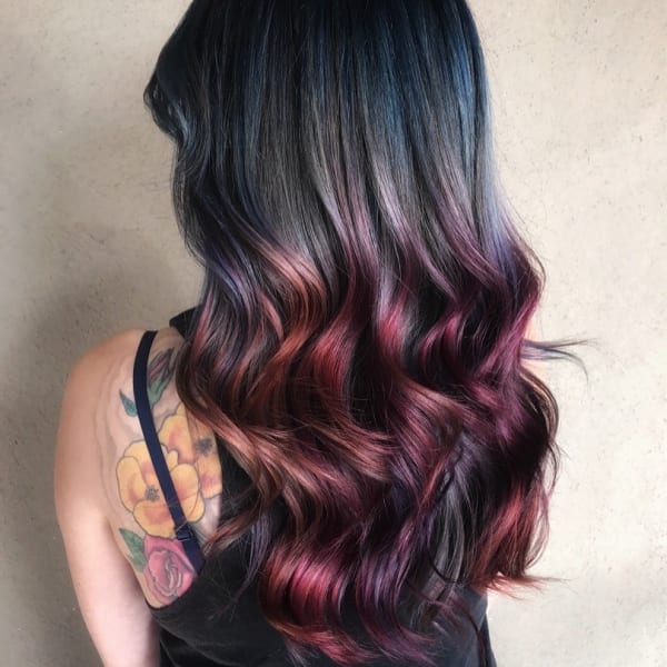 A brunette woman with pieces of bright color throughout her hair.