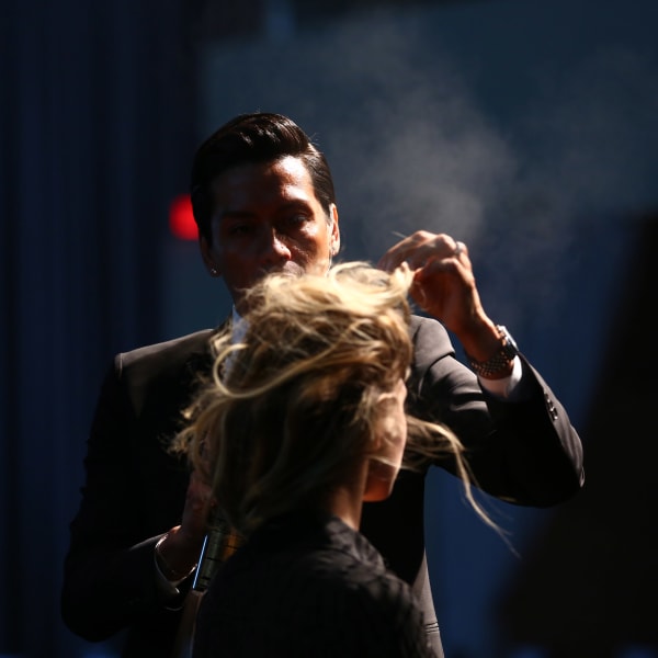 A man spraying hairspray on a model