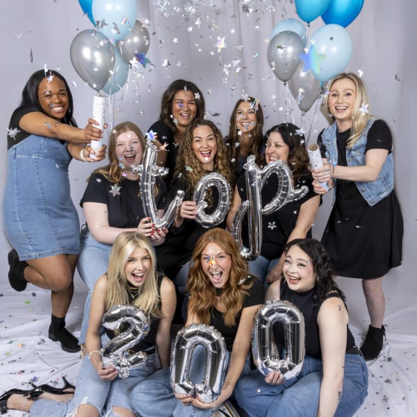 Surrounded by balloons and holding champagne, the excited team from Pure Salon Spa.