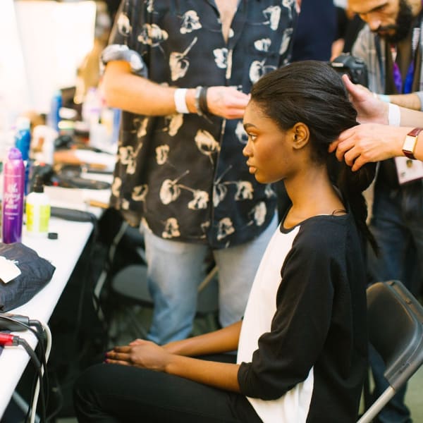 A model has her hair arranged by a hairdresser.