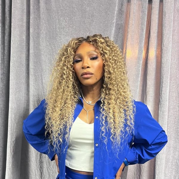 A woman with long curly hair, standing.