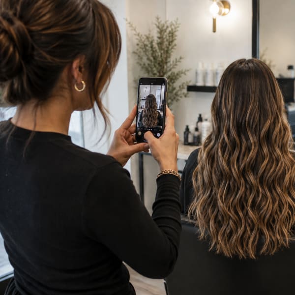 A stylist takes an after photo of her clients hair.