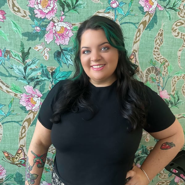a woman standing against a green floral background