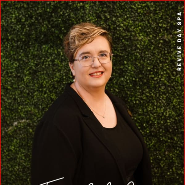 A photo of a woman in black against a green wall.