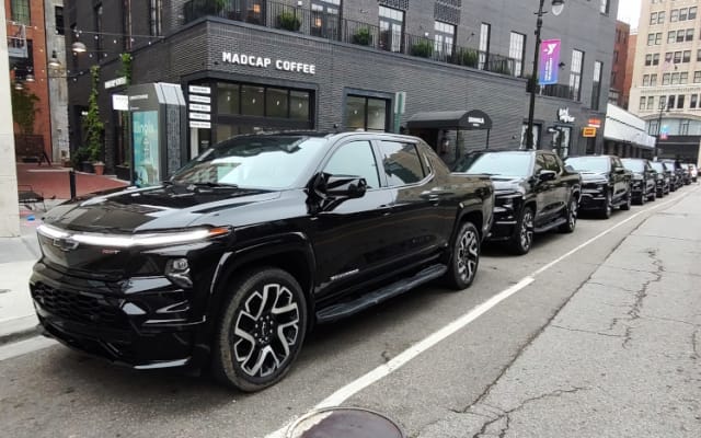 A row of black pickup trucks shown parked in downtown Detroit.