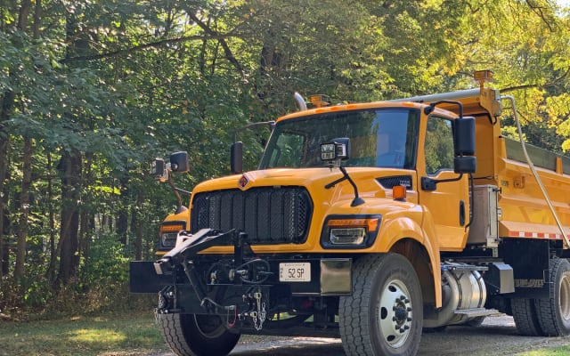 Yellow International HV truck on gravel road in the woods