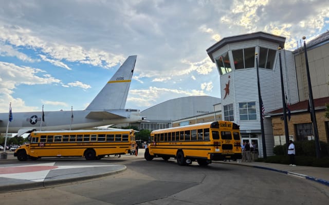 Two school buses parked in front of the Wings Over the Rockies Air & Space Museum in Denver.