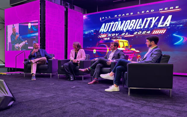 Photo of three panelists on stage during a seminar at LA Auto Show. 