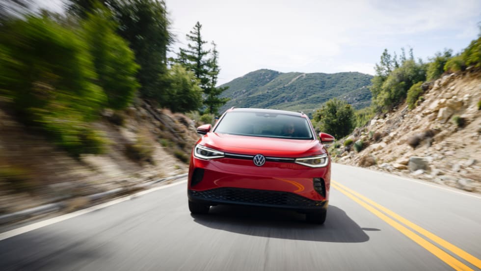 A red Volkswagen ID.4 is seen driving down a winding, mountainous road.