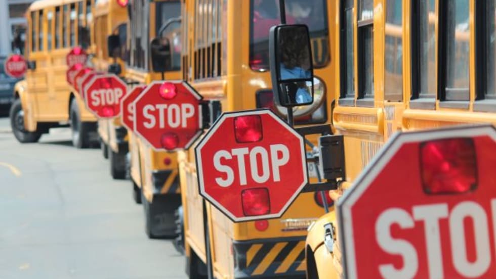 a photo of multiple buses with their stop-arm out