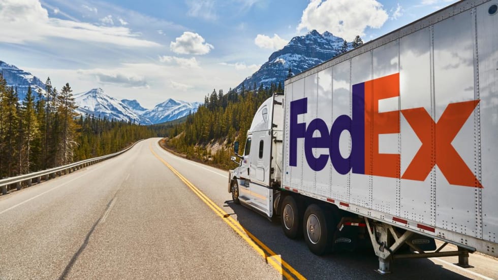 FedEx tractor-trailer on highway with mountains in background