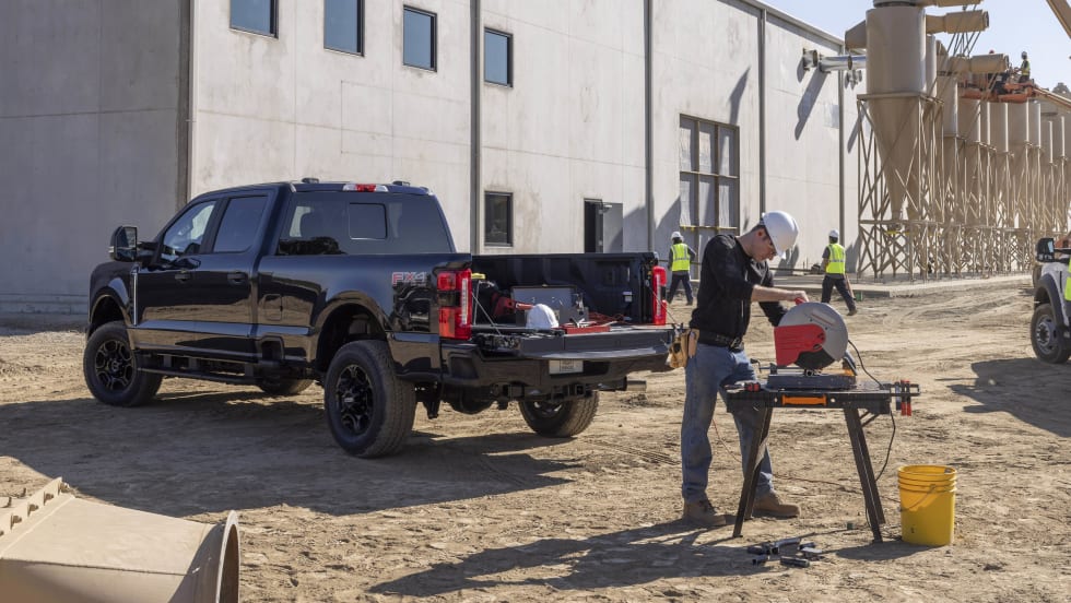 A man is seen using a saw powered by a black 2024 Ford F-250 XL STX Appearance Package.