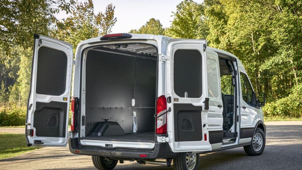 A white Ford Transit van rear three-quarter view with back doors and side door open.