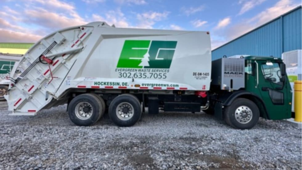 Electric refuse truck parked, facing right with EG logo on the side.