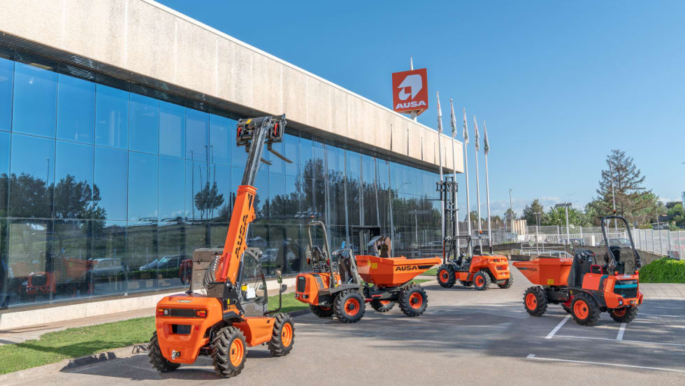 Orange small construction vehicles including forklifts and small dump trucks are parked outside and office.