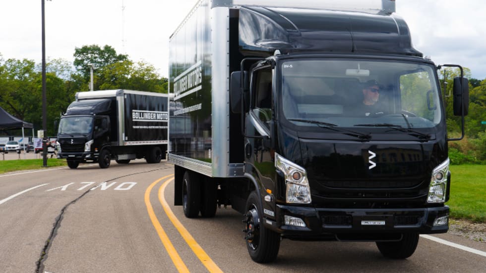 Two black-cab box trucks driving toward the camera.