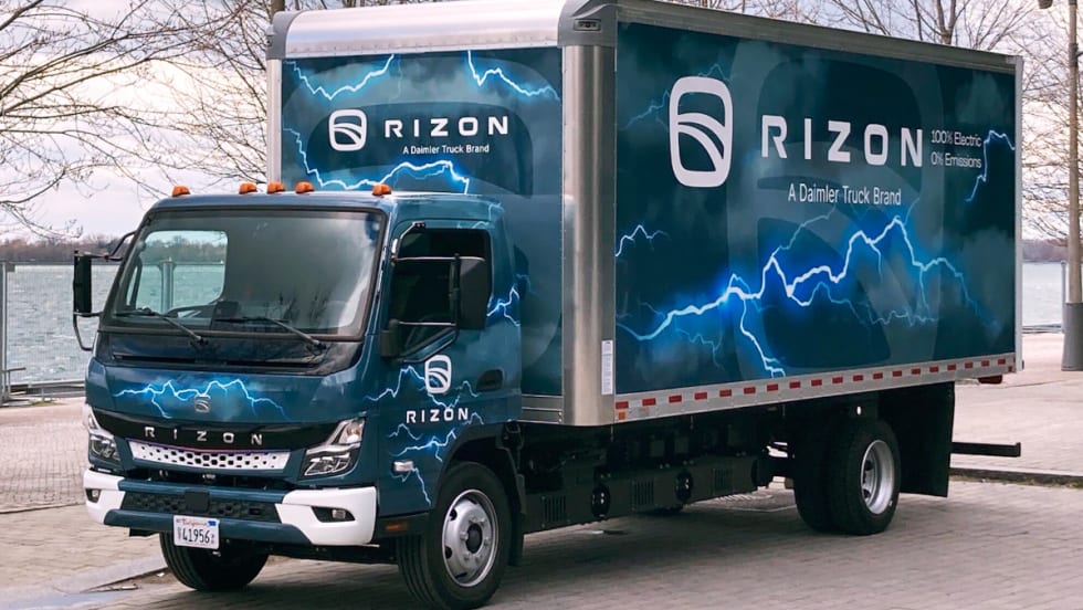 Blue box truck with Rizon on the side of the box parked by a lake.