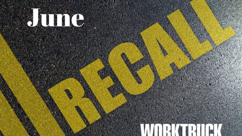 Close up image of a road, with double yellow line angled on the left and yellow lettering that says RECALL.