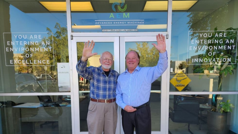 Robert and Ron Koelsch wave in front of the AEM headquarters building.