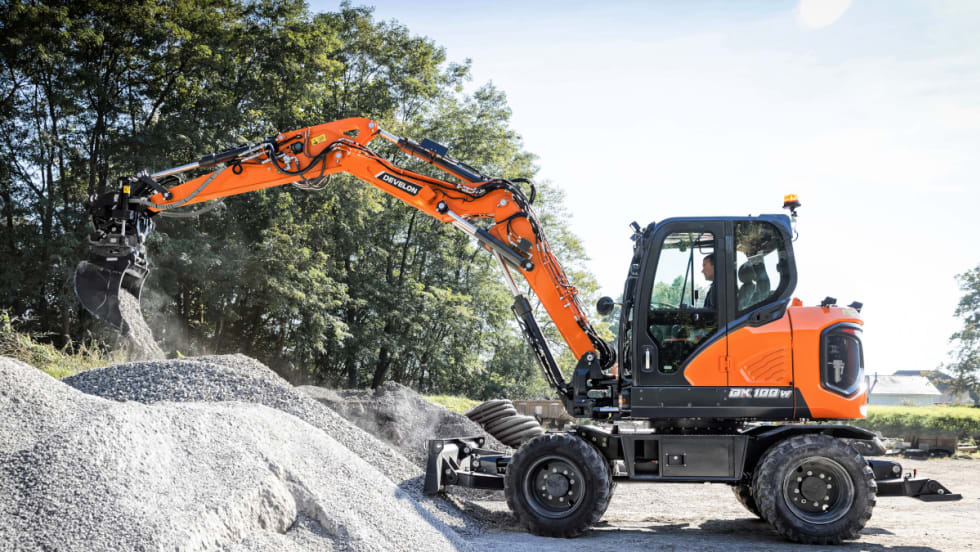 Orange wheel excavator is digging into a pile of gravel.