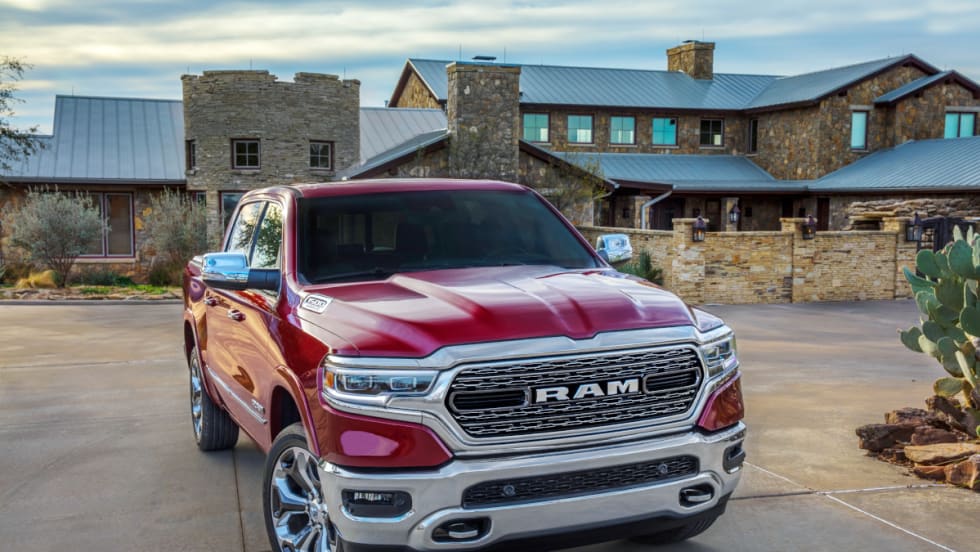 Red Ram 1500 pickup parked in front of a large house.