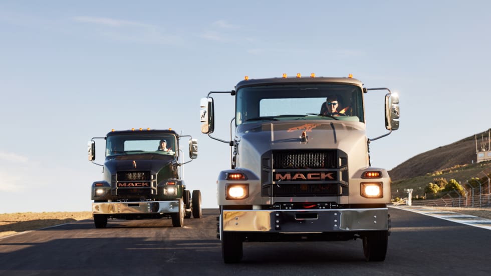 Two medium-duty chassis cab trucks driving toward the camera.