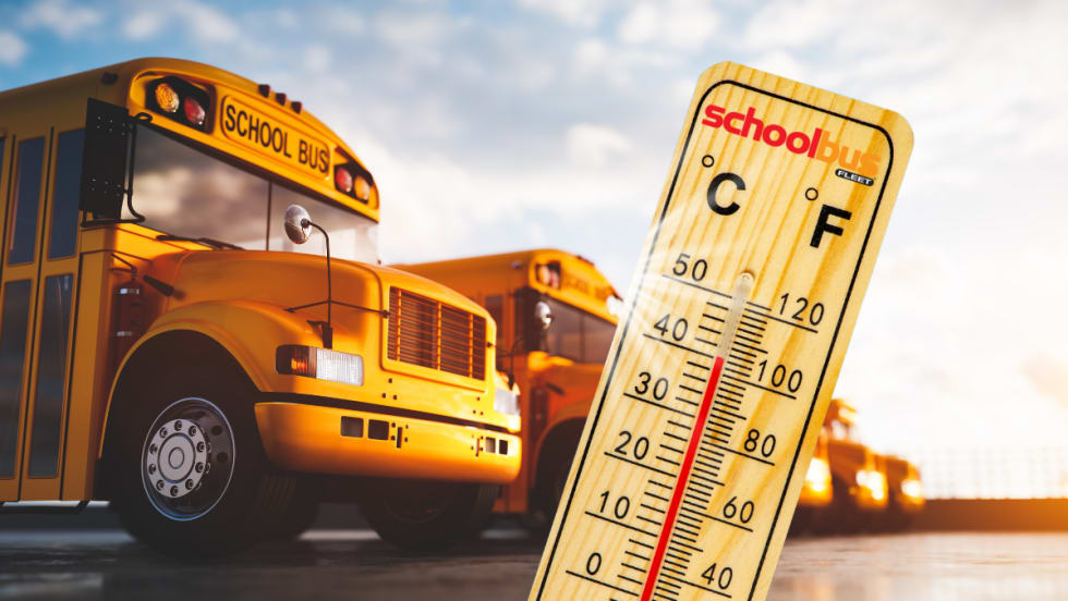 School buses in the sun with a thermometer in front.