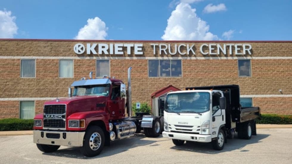 Two trucks parked in front of an industrial building.
