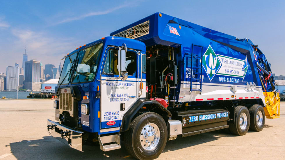 A blue and white garbage truck parked on the street.