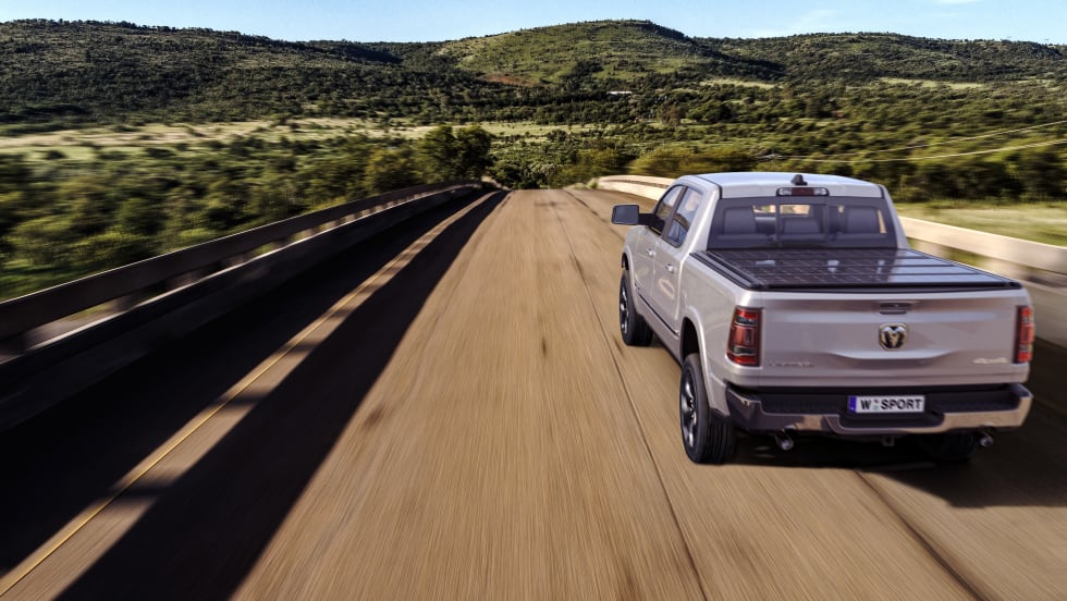 A road with a Ram 1500 equipped with a tonneau cover.