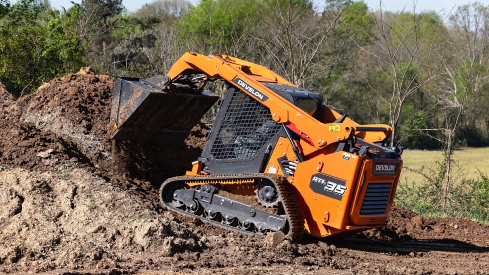 Image of a compact orange digging machine excavating the ground.