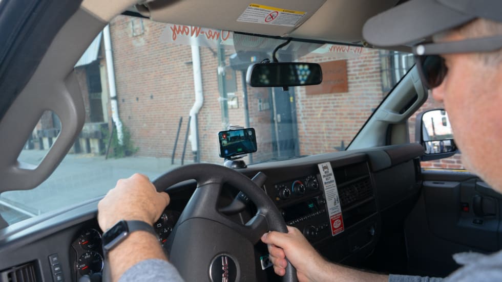 Image of a man behind the wheel of a truck with a dashboard camera in use.