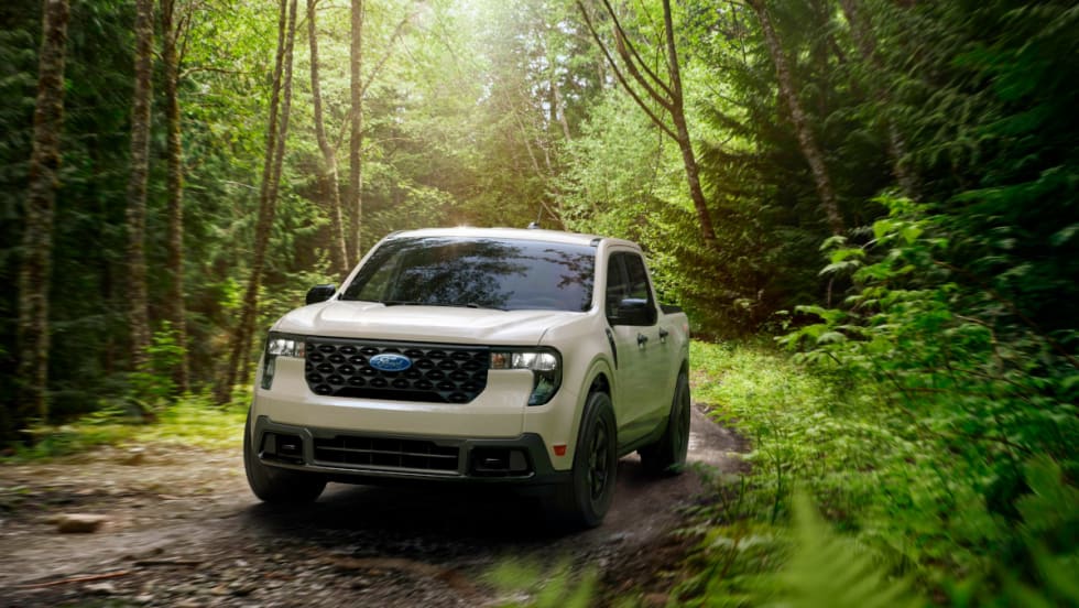 Pickup truck driving on a dirt road through a forest.