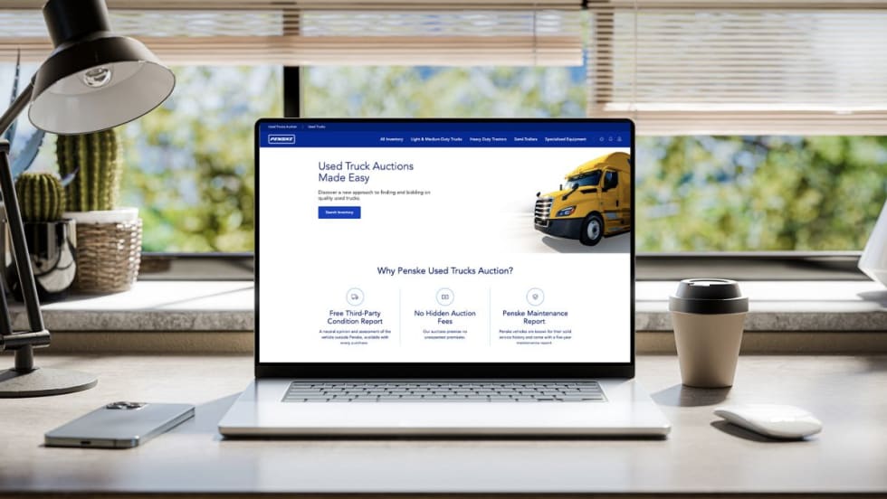 Laptop with Penske Used Truck auctions on screen