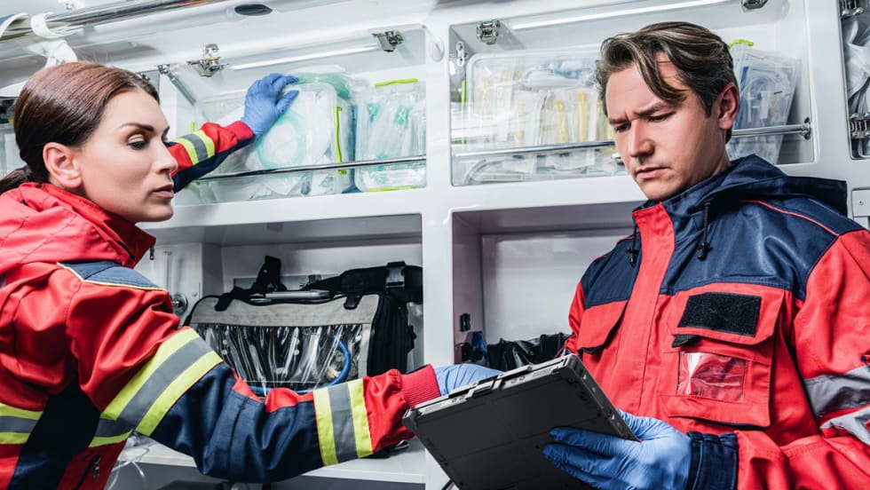 Emergency medical technicians reviewing medical equipment inside ambulance