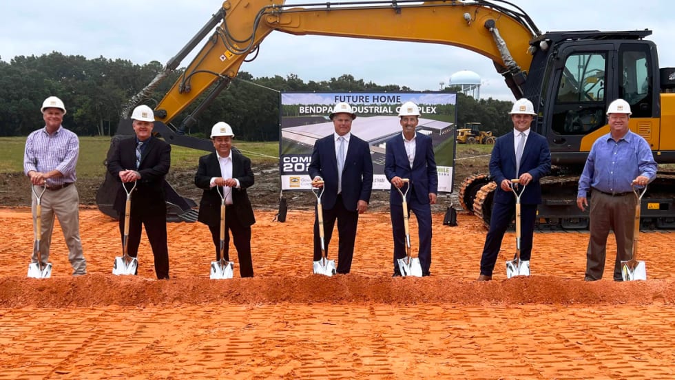 Business and city leaders pose with shovels at groundbreaking event.